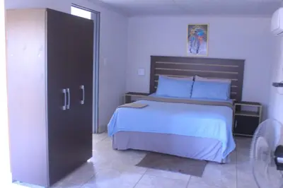 a bedroom with a large bed with a wooden headboard at Exodus Guesthouse Mahlakwena Stee'lpoort in Steelpoort