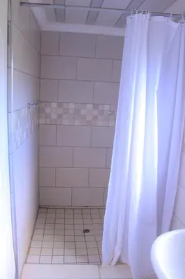 a shower with a white shower curtain in a bathroom at Exodus Guesthouse Mahlakwena Stee'lpoort in Steelpoort