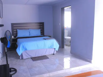 a blue bedroom with a bed and a bathroom at Exodus Guesthouse Mahlakwena Stee'lpoort in Steelpoort