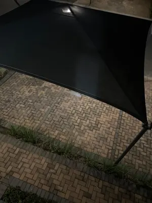 a black umbrella sitting on a brick sidewalk at 5 Bronco The Polofields in Midrand