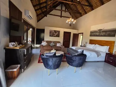 a bedroom with a bed and a desk and chairs at 76 Zebula- Premium Luxurious Villa in Bela-Bela! in Warmbaths