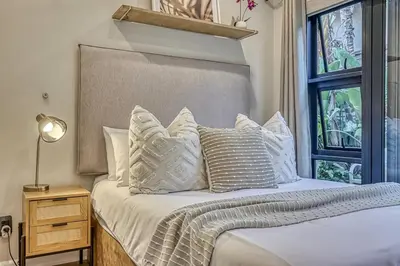 a bedroom with a bed with white pillows and a window at Pecanwood Summit Shores Villa in Hartbeespoort