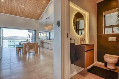 a bathroom with a toilet and a dining room at Pecanwood Summit Shores Villa in Hartbeespoort