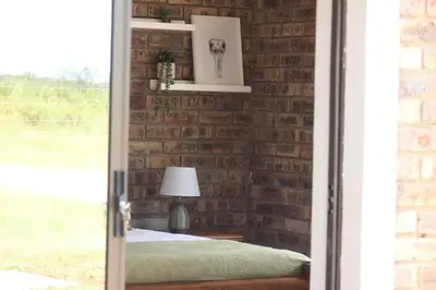 a brick bedroom with a bed and a lamp at Little Amanzi in Pienaarsrivier