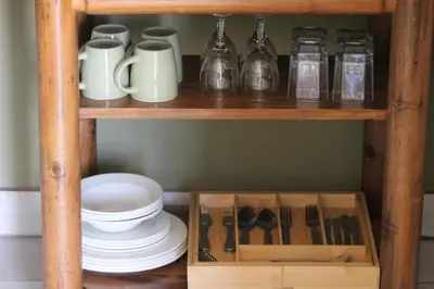 a wooden shelf with dishes and utensils on it at Little Amanzi in Pienaarsrivier
