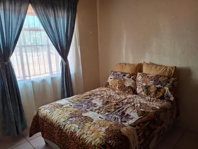a bedroom with a bed and a window with blue curtains at Mpofu Farming and Guesthouses in Musina