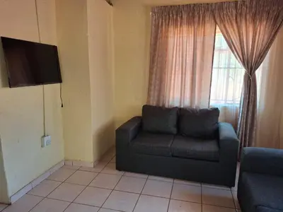 a living room with a couch and a window at Mpofu Farming and Guesthouses in Musina