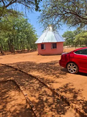 a red car parked in front of a red building at Mpofu Farming and Guesthouses in Musina