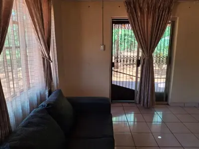 a living room with a couch and a sliding glass door at Mpofu Farming and Guesthouses in Musina