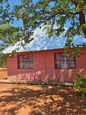 a red house with a metal roof at Mpofu Farming and Guesthouses in Musina