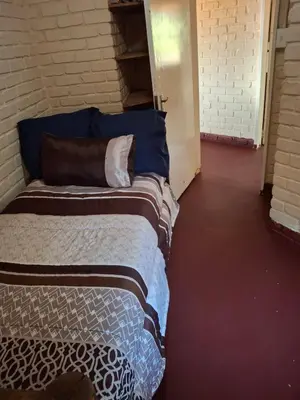 a bedroom with two beds in a brick wall at Mpofu Farming and Guesthouses in Musina