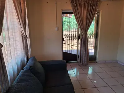 a living room with a couch and a sliding glass door at Mpofu Farming and Guesthouses in Musina