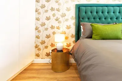 a bed with a blue headboard and a lamp on a table at #Alimama Spaces The Manson's Steyn City in Midrand