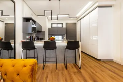 a kitchen with black stools and a kitchen with white cabinets at #Alimama Spaces The Manson's Steyn City in Midrand