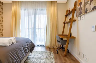 a bedroom with a bed and a desk and a window at #Alimama Spaces The Manson's Steyn City in Midrand