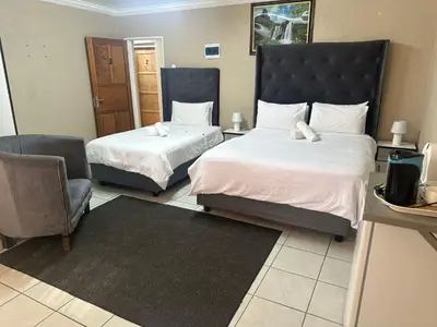 a hotel room with two beds and a chair at 373 Guest House in Pretoria