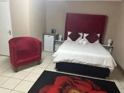a bedroom with a bed and a red chair at 373 Guest House in Pretoria