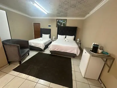 a room with two beds and a chair and a couch at 373 Guest House in Pretoria