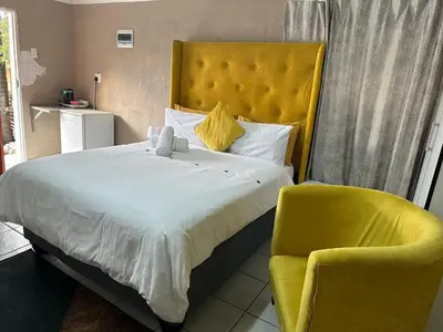a bedroom with a bed and a yellow chair at 373 Guest House in Pretoria