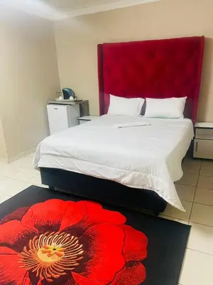 a bedroom with a large bed with a red headboard at 373 Guest House in Pretoria