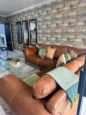 a living room with leather couches and a brick wall at The lagoon retreat in Avondzon