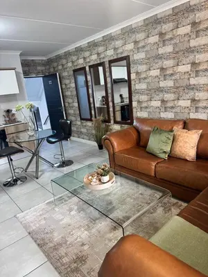 a living room with a leather couch and a table at The lagoon retreat in Avondzon