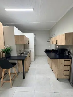 a large kitchen with a black counter and wooden cabinets at Green Haven Waitara in Tzaneen