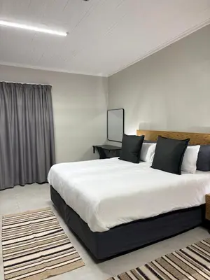 a bedroom with a large white bed with black pillows at Green Haven Waitara in Tzaneen