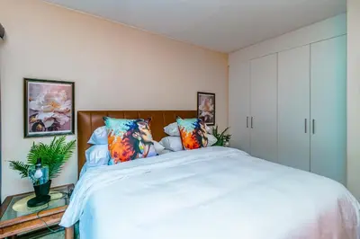a bedroom with a large white bed with colorful pillows at Urban Tuscany Apartment in Sandton