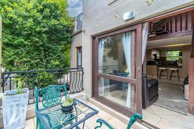 a balcony with a bench and a sliding glass door at Urban Tuscany Apartment in Sandton