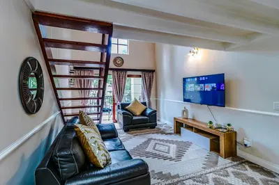a living room with a leather couch and a television at Urban Tuscany Apartment in Sandton
