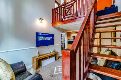 a living room with a staircase and a tv at Urban Tuscany Apartment in Sandton