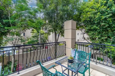 two green chairs and a table on a balcony at Urban Tuscany Apartment in Sandton