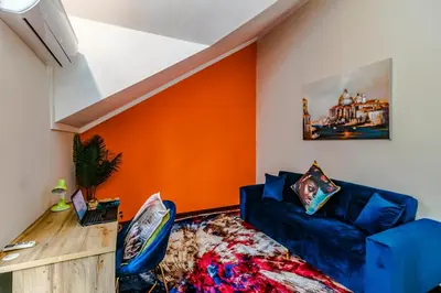 a living room with a blue couch and an orange wall at Urban Tuscany Apartment in Sandton