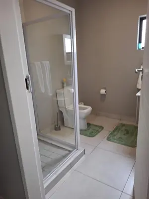 a bathroom with a toilet and a glass shower door at Oak and Olive Retreat Midrand in Midrand