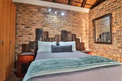 a bedroom with a brick wall and a bed at Inyathi in Marloth Park