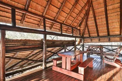 a wooden table and bench in a straw hut at Inyathi in Marloth Park