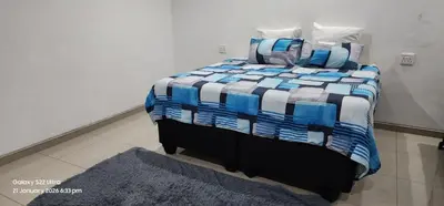 a bed with a blue and white blanket on it at Thohoyandou P house rooms in Thohoyandou