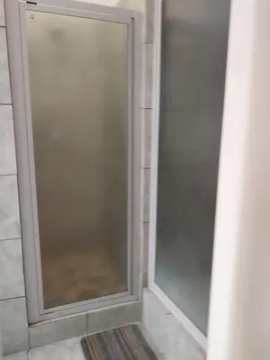 a glass shower door in a bathroom at Roullas gardens in Pretoria