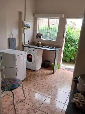 a kitchen with a washing machine and a table at Roullas gardens in Pretoria