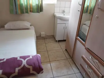 a small bathroom with a bed and a sink at Roullas gardens in Pretoria