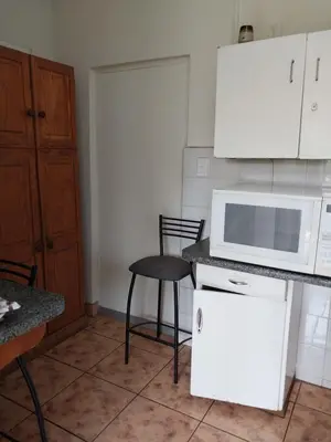 a kitchen with a white microwave and a chair at Roullas gardens in Pretoria