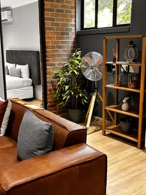 a living room with a brown couch and a brick wall at 101 Brooklyn Stylish Apartment in Pretoria