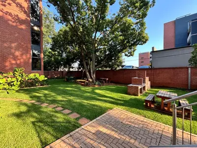 a yard with a tree and a brick building at 101 Brooklyn Stylish Apartment in Pretoria