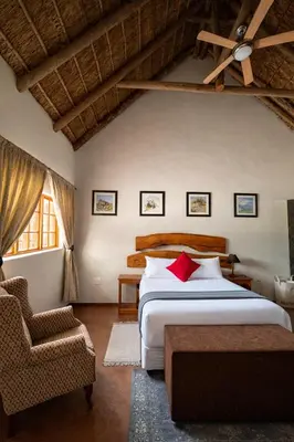 a bedroom with a large bed and a chair at Mathendele Bush Lodge in Oporto