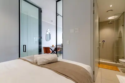 a bedroom with a large bed and a bathroom at AlimamaSpaces Moskit's Newton Place in Midrand