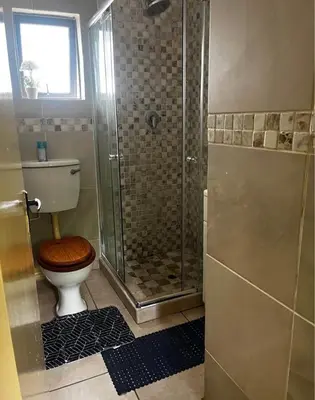 a bathroom with a toilet with a glass shower at Bra Phuti' Place in Pretoria