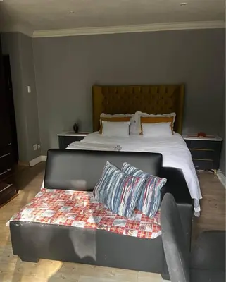a bedroom with a bed with a bench with pillows at Bra Phuti' Place in Pretoria