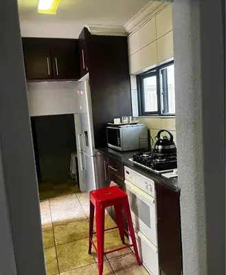 a kitchen with a red stool in a kitchen at Bra Phuti' Place in Pretoria