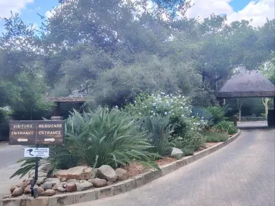 a sign in a garden with flowers and plants at The Lofts in Hoedspruit